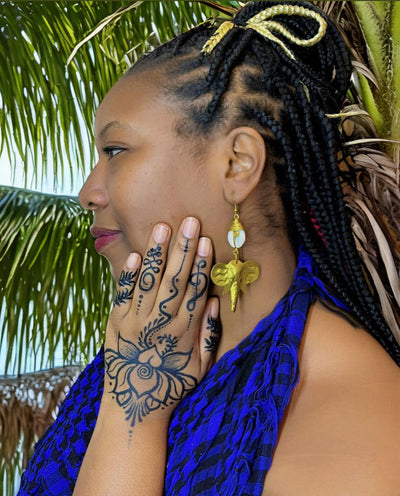 black woman wearing henna and elephant earrings, brass, cowrie shell
